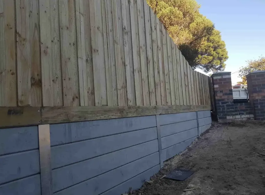Grey concrete sleeper retaining wall with timber fence above